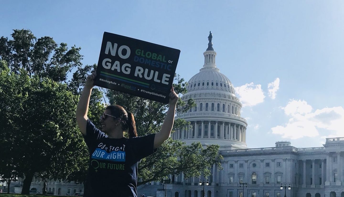 activist holds sign in front of U.S. Capitol that says 