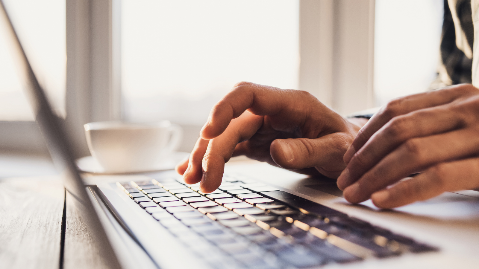 two hands hovering over a laptop keyboard