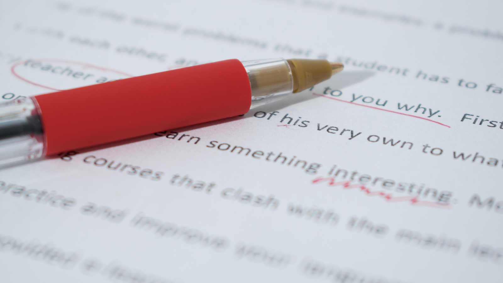 red ink pen lays on top of document being edited